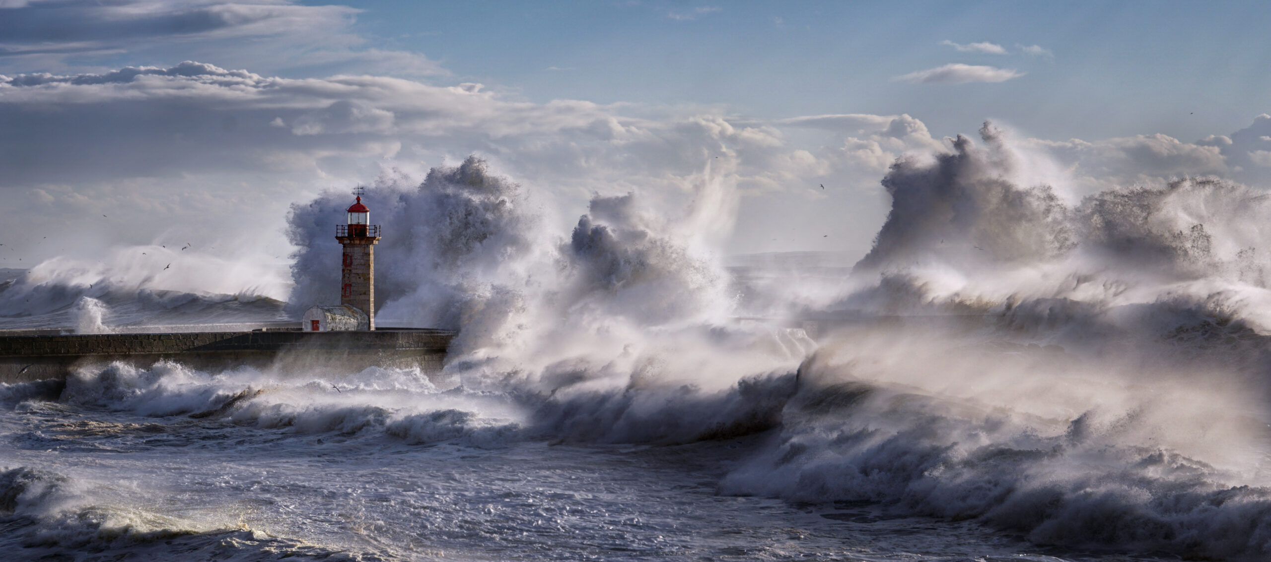 Lighthouse standing against large crashing waves